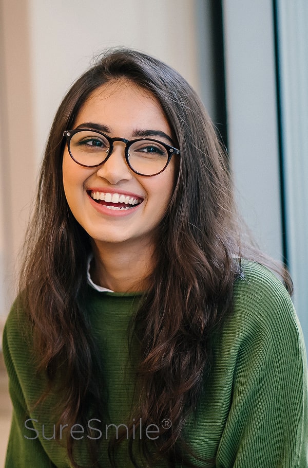 Transform Your Smile with SureSmile® – Fast, Precise, and Comfortable Orthodontic Treatment. A girl in a sweeter is smiling